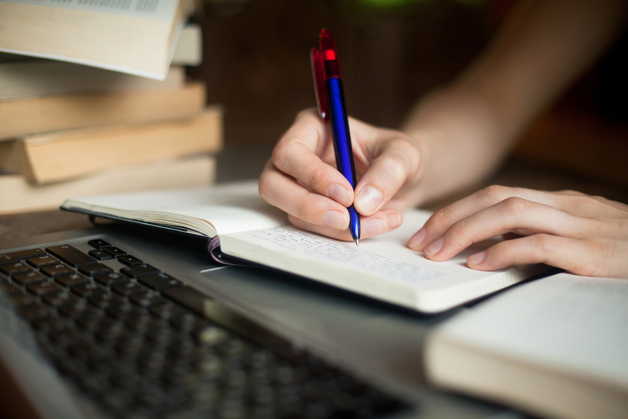 Student taking notes in journal, inside library